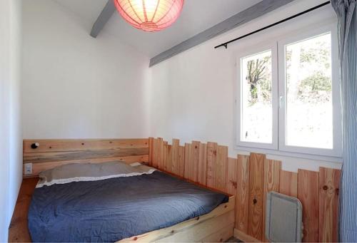 1 dormitorio con cama de madera y ventana en Maison à Flayosc, entre la mer et le Verdon., en Flayosc