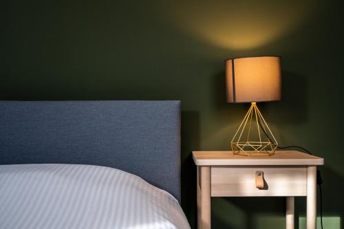 a lamp on a nightstand next to a bed at General Sixty-Seven by Romy&Travis in Bruges