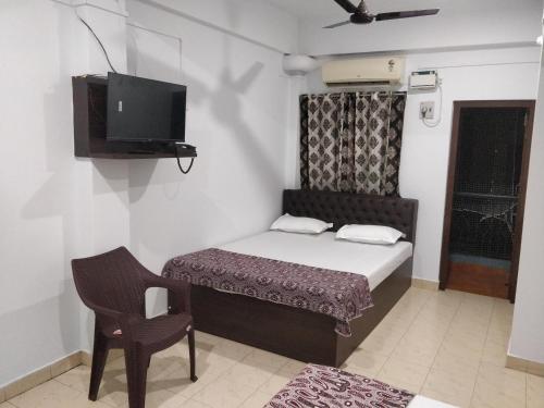 a small room with a bed and a chair and a tv at Adarsh Hotel in Port Blair