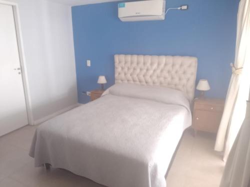 - une chambre avec un lit blanc et un mur bleu dans l'établissement Casa amplia con pileta 9 personas, à Luján de Cuyo