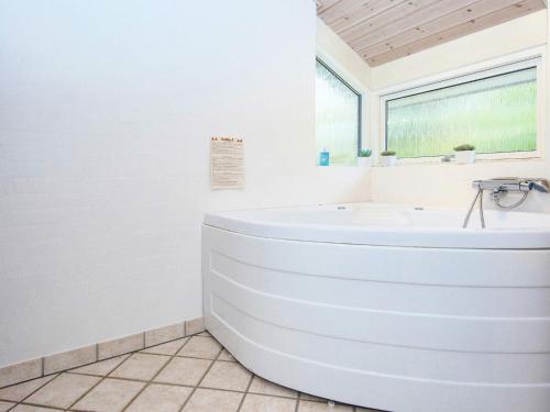 a white bathroom with a tub and a window at 8 person holiday home in Grenaa in Grenå