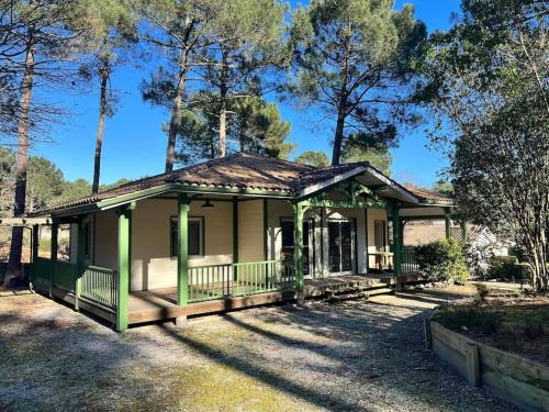 une petite maison verte avec une terrasse couverte dans l'établissement La Landaise au golf de Biscarosse, à Biscarrosse