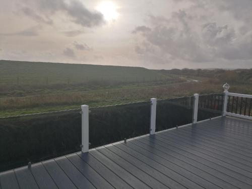 a wooden deck with a view of a field at Rye Harbour Holiday Park in Rye Harbour