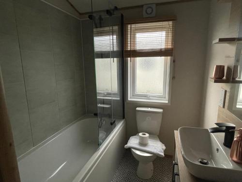 a bathroom with a tub and a toilet and a sink at Rye Harbour Holiday Park in Rye Harbour