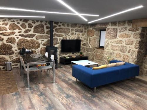 a living room with a blue couch and a stone wall at Casa Velha Azeitona in Tábua