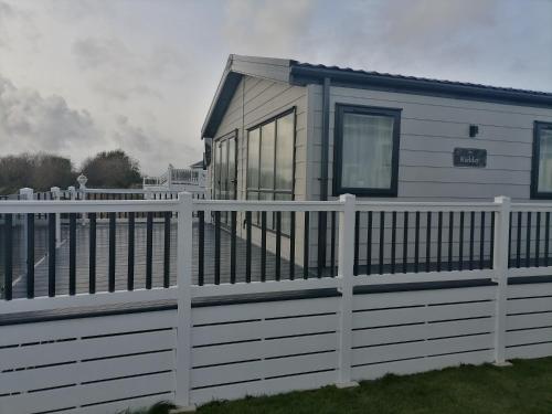 a house with a white fence at Rye Harbour Holiday Park in Rye Harbour
