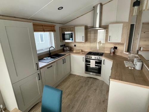 a kitchen with white cabinets and a blue chair in it at Rye Harbour Holiday Park in Rye Harbour