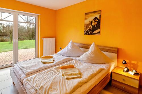 a bedroom with a large bed with orange walls at Mediterranes Flair mit Seeblick in Nenndorf