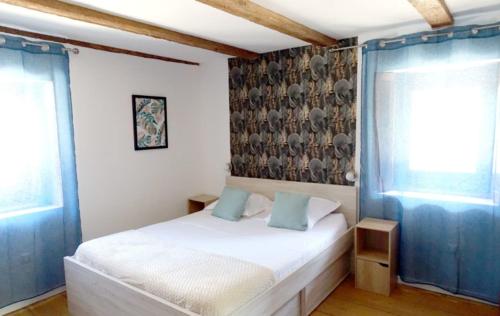 1 dormitorio con cama blanca y almohadas azules en La Tour de Coron, en Belley