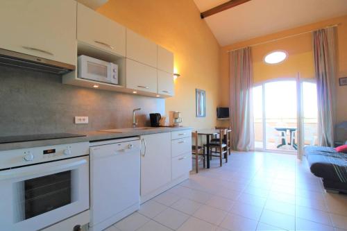 Il comprend un salon et une cuisine équipée d'appareils électroménagers blancs. dans l'établissement GASQUEN - Golfe de St-Tropez - Aux Marines de Gassin Duplex pour 7 personnes, à Gassin