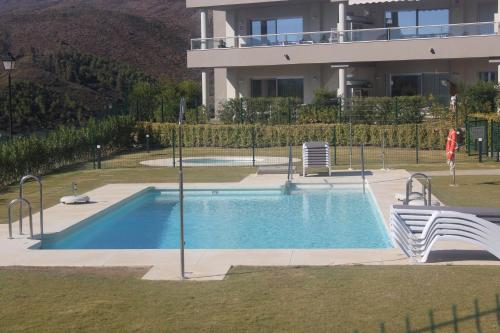 una piscina con 2 sillas y un edificio en La Cala de Mijas Apartment, en Málaga