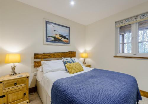 a bedroom with a blue and white bed and a window at Badger in Postling
