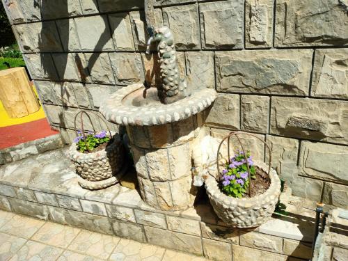 a fountain with three baskets of flowers on a stone wall at Apartman Zvijerko in Trebinje