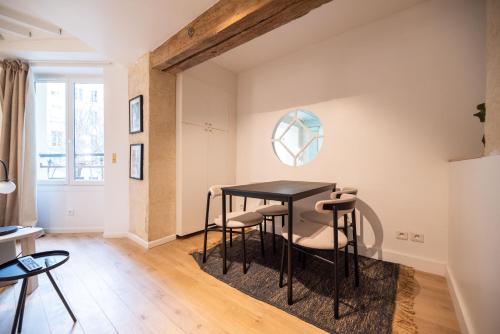 une salle à manger avec une table noire et des tabourets dans l'établissement Cosy Nest in Saint Germain, à Paris