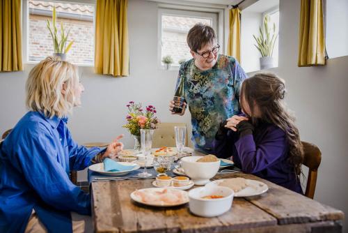 three women sitting around a table eating food at B&B Art.14 in Morkhoven