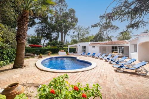 a backyard with a pool and chairs and a house at Villa AlGharif by Algarve Vacation in Albufeira