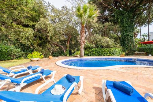 a swimming pool with blue and white lounge chairs next to a swimming pool at Villa AlGharif by Algarve Vacation in Albufeira