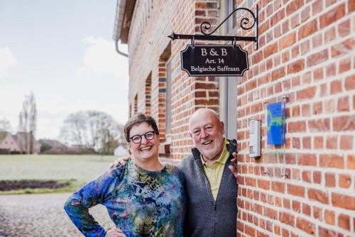 two men are standing next to a brick wall at B&B Art.14 in Morkhoven