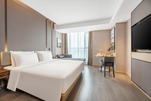 a hotel room with a large white bed and a table at Atour Hotel Xi'an Chanba Exhibition Center Expo Park in Xi'an