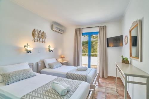 a bedroom with two beds and a balcony at Pano Stalos Villas in Stalos