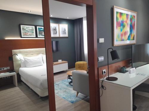 サン・セバスティアンにあるHotel Silken Amara Plazaのベッド、デスク、椅子が備わるホテルルームです。