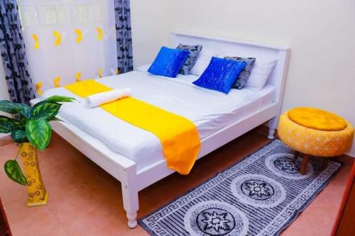 1 dormitorio con 1 cama con almohadas azules y amarillas en Naivasha 2 Bedroom Rated Best, en Naivasha