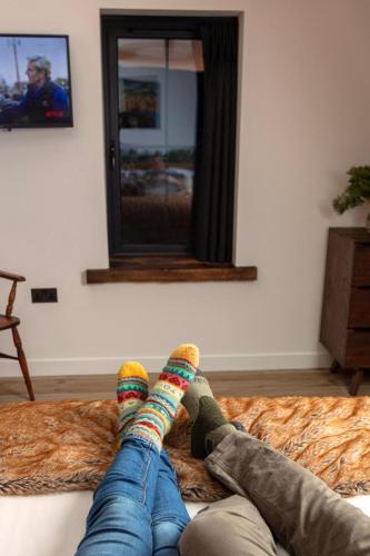 a person laying on a bed with their feet in colorful socks at The Ruin - Wood fired hot tub - Lochside - Dog friendly in Ullapool