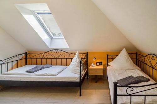 2 bedden in een zolderslaapkamer met een dakraam bij Haus mit Seeblick in Nenndorf