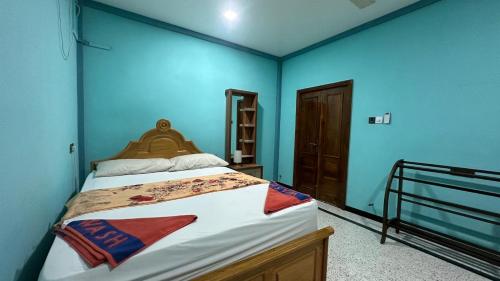 1 dormitorio con 1 cama grande y paredes azules en Santhosh Villa, en Point Pedro