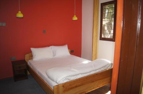 a bed in a room with a red wall at Blue Cactus Shanty in Moshi