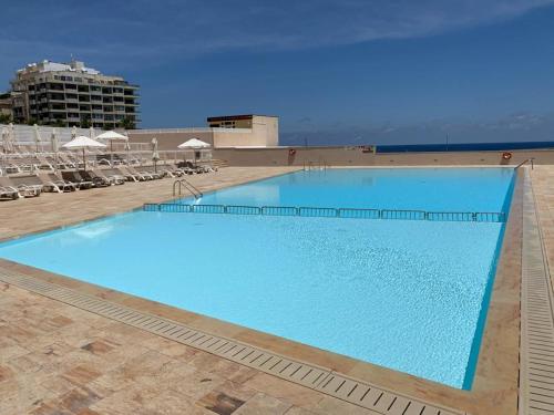 une grande piscine bleue avec des chaises et un bâtiment dans l'établissement Seaview terrace, 2bedrooms, communal pool COGO1-1, à Sliema