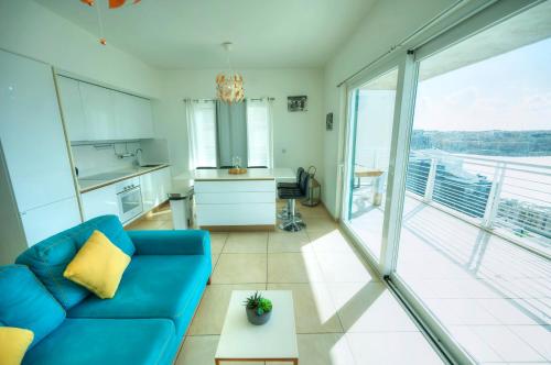 a living room with a blue couch and a kitchen at Seaview terrace, 2bedrooms, communal pool COGO1-1 in Sliema
