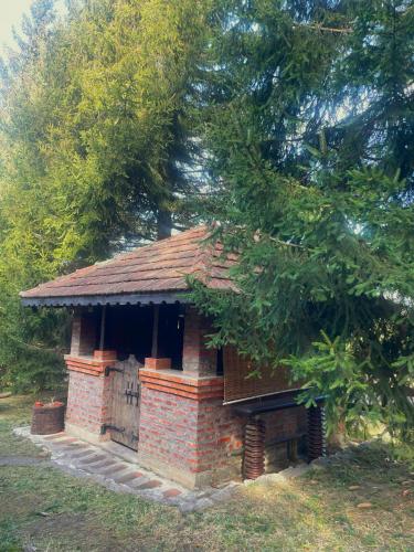 a small brick building with a door under a tree at Kućica za odmor '' Idila '' in Mitrovac
