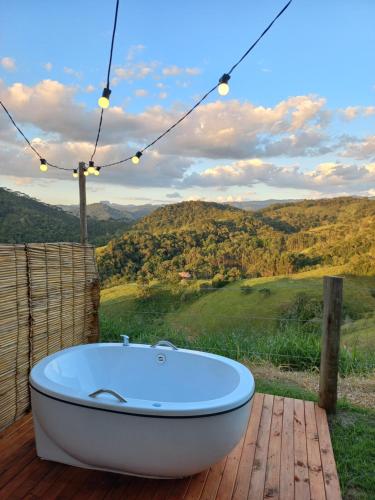 a bath tub sitting on a deck with a view at Embahu Suítes - Vista para Pedra do Baú e banheira de imersão in Santo Antônio do Pinhal