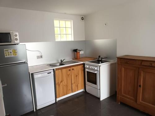 une cuisine avec des appareils électroménagers blancs et des armoires en bois dans l'établissement La Casita, au paradis du surf, à Maubuisson