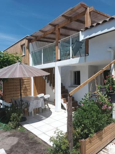 un patio avec une table et un parasol dans l'établissement La Casita, au paradis du surf, à Maubuisson
