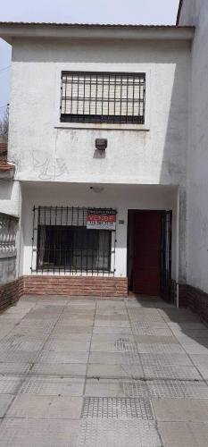 um edifício branco com uma porta e uma janela em Santa Teresita Alquila Duplex em Santa Teresita
