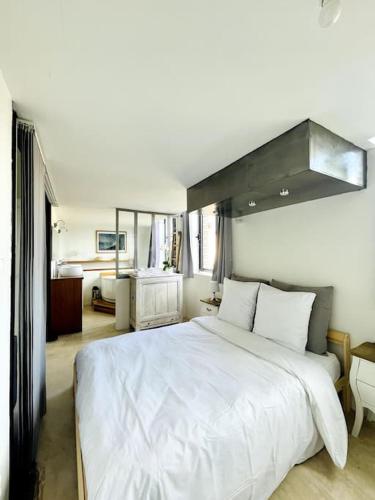 1 dormitorio con 1 cama blanca grande y baño en Le Loft -Superbe volume- en Saint-Étienne