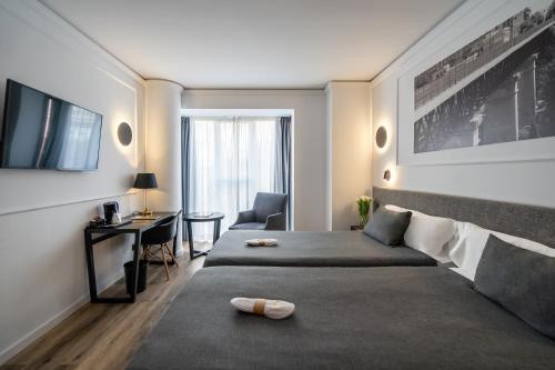 Habitación de hotel con cama, escritorio y TV. en Hotel Conqueridor, en Valencia