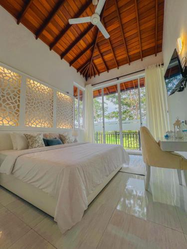 een slaapkamer met een groot bed en een plafondventilator bij Sunset Villa in Waskaduwa