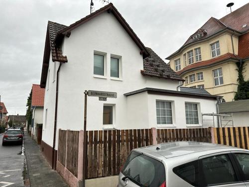 ein weißes Haus mit einem Zaun und einem Auto vor dem Haus in der Unterkunft Rona 2xZimmerwohnung in Darmstadt
