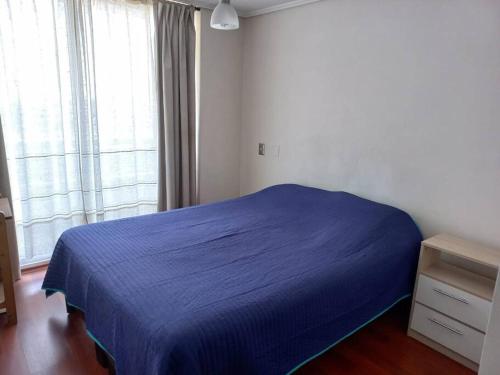Un dormitorio con una cama azul y una ventana en Departamento Valparaíso, en Valparaíso