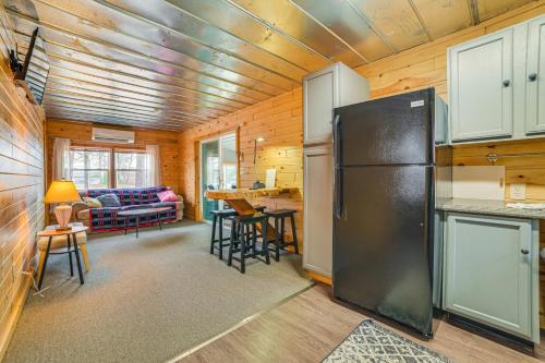 a kitchen with a refrigerator and a living room at Oscoda Cabin with Charcoal Grill Walk to Lake Huron in Oscoda