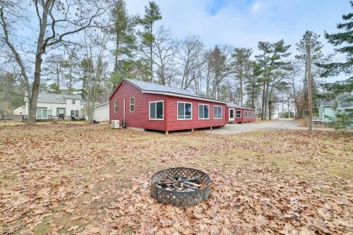 a red cabin in a yard with a fire pit at Oscoda Cabin with Charcoal Grill Walk to Lake Huron in Oscoda