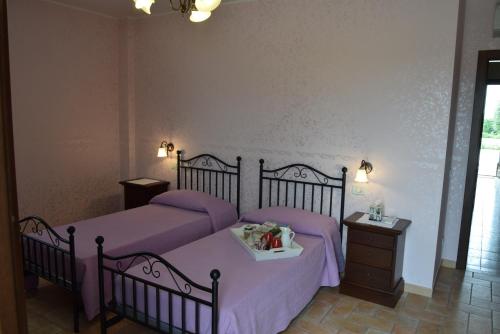 a bedroom with two beds with purple sheets at Postiglione Country House in Cingoli