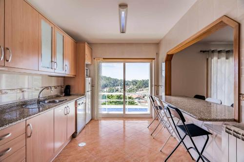 a kitchen with a counter and a large window at Casal do Porto - Um refugio de férias in Vila Verde