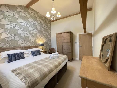 a bedroom with a large bed and a wall at Sheepfold Barn in Penruddock