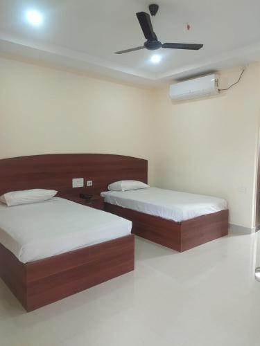 a bedroom with two beds and a ceiling fan at The Royal Residency in Rājgīr