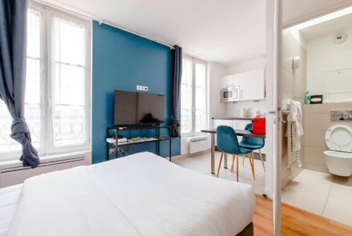 sypialnia z białym łóżkiem i niebieską ścianą w obiekcie Le Studio Versaillais w Wersalu