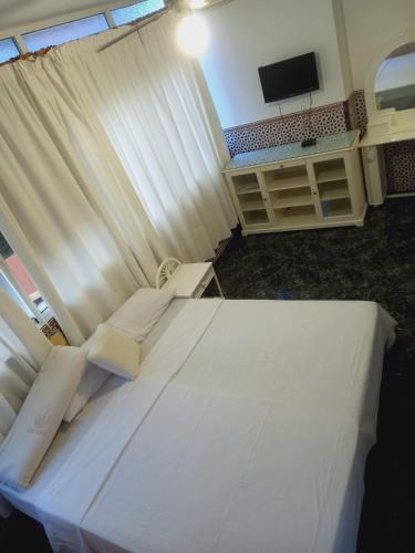 1 dormitorio con 1 cama blanca grande y TV en Lounge estrella en Benalmádena